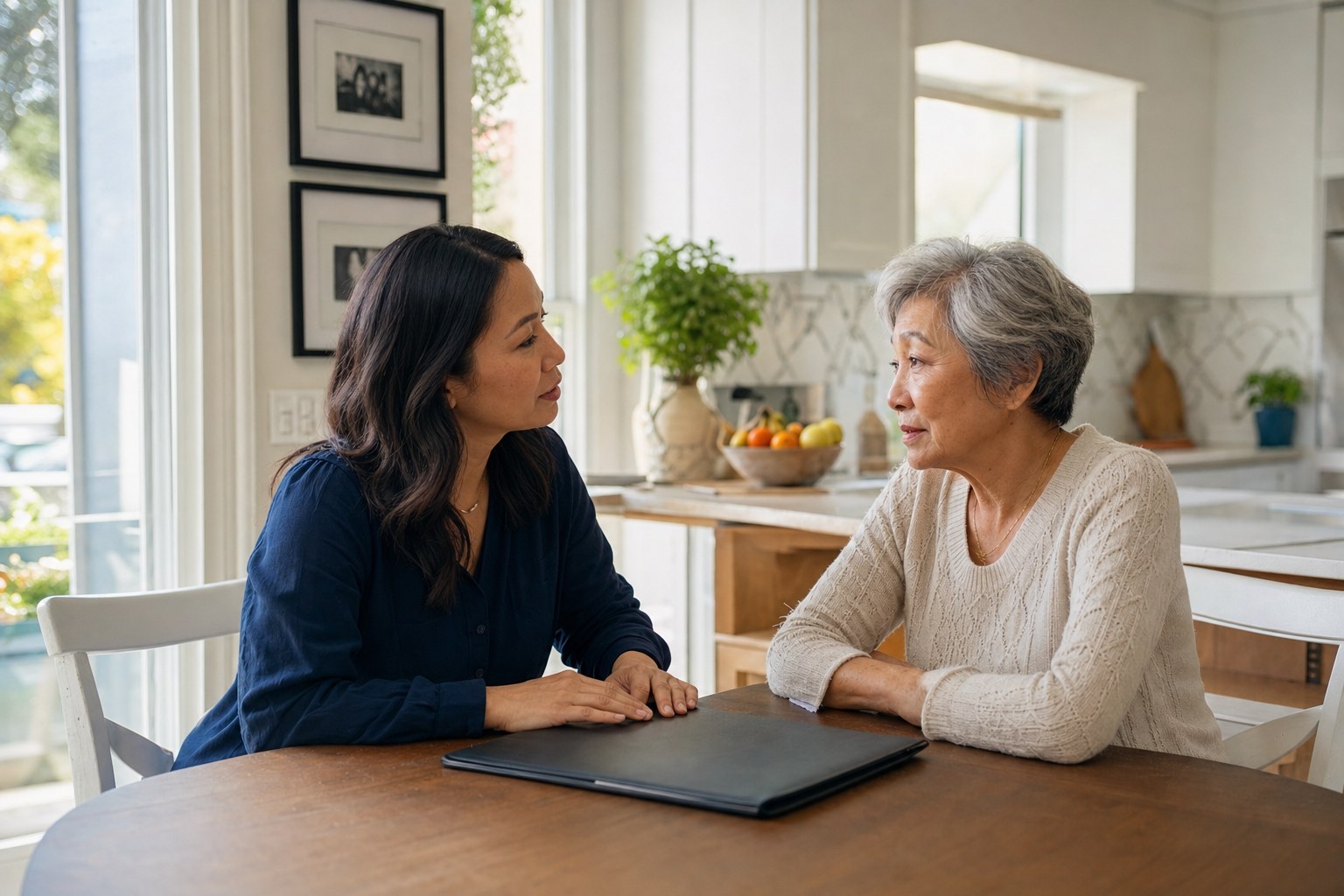 Adult daughter and older mother having a focused conversation at a kitchen table